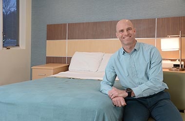 Kenneth Plowman leaning against clinic bed